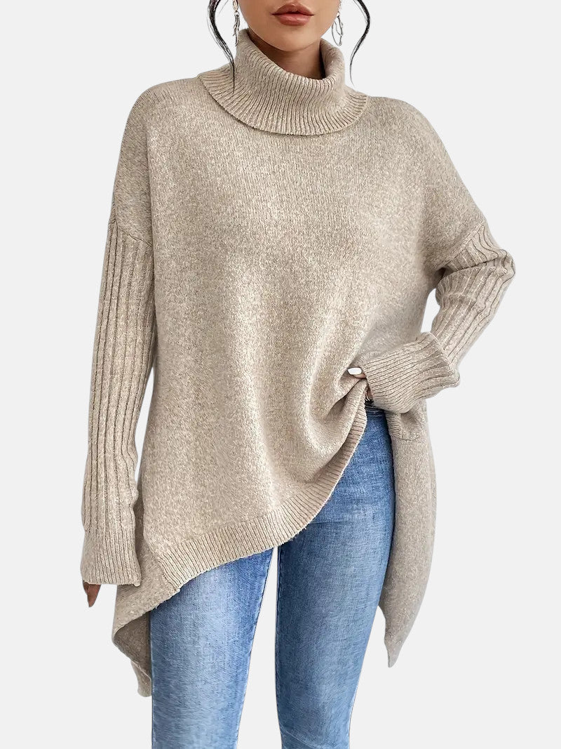 Camel long turtleneck sweater with ribbed sleeves and relaxed fit, worn with blue jeans.