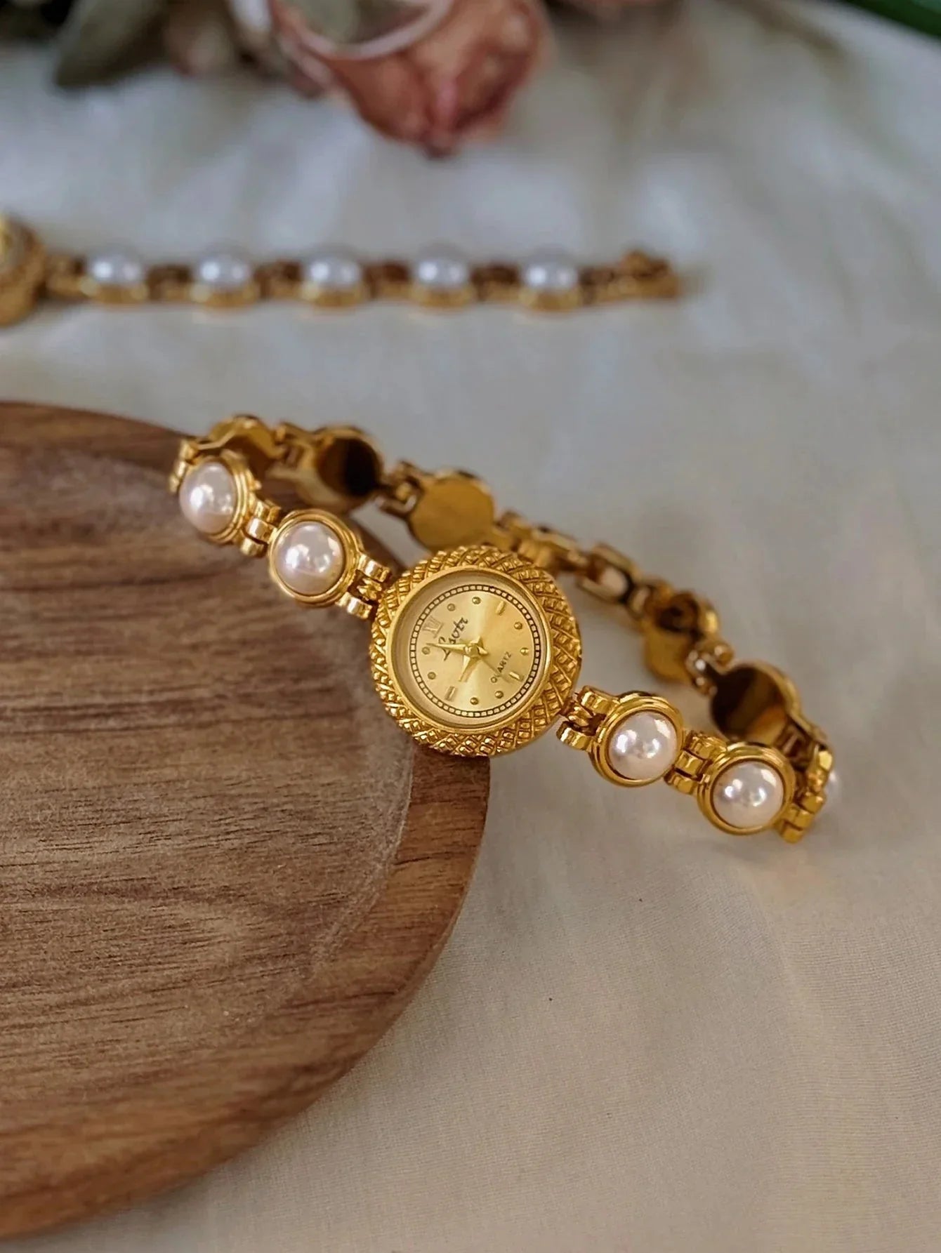 Gold bracelet with pearl accents on a wooden surface