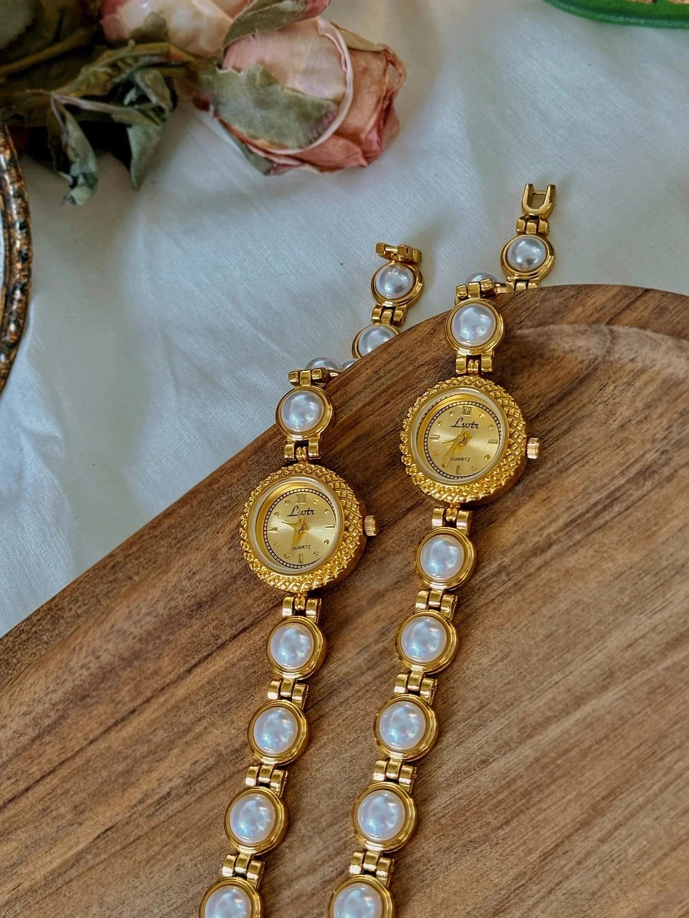 Gold jewelry set with pearl accents on a wooden surface
