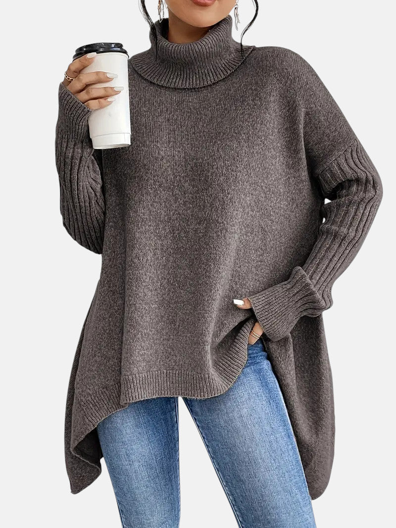 Long charcoal gray turtleneck sweater with ribbed sleeves and side slits, worn with blue jeans.