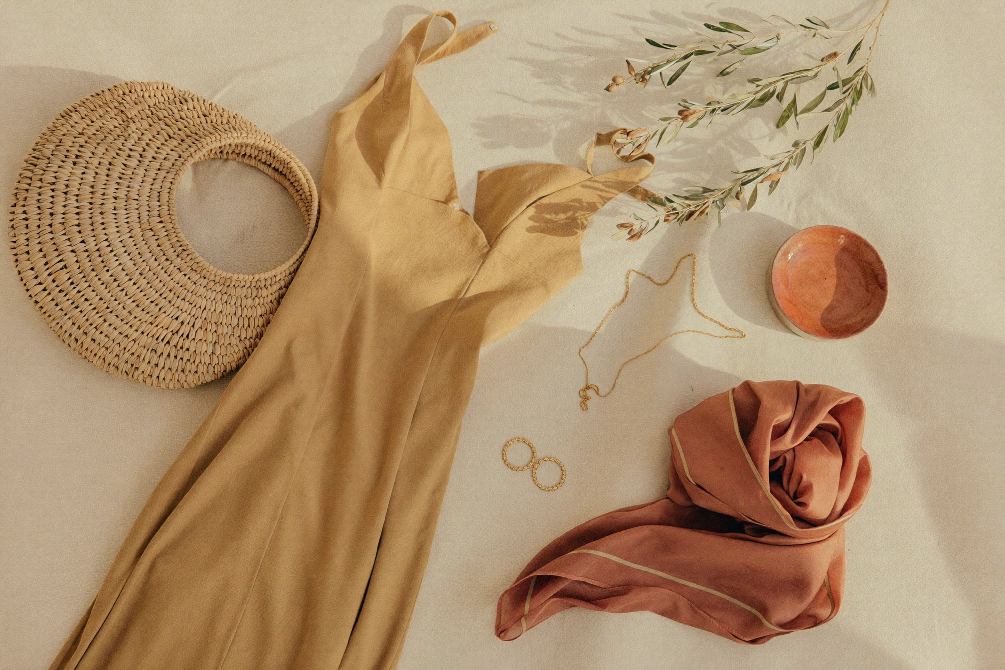 How to wear a maxi dress — flat lay of a sand maxi dress with straw bag and gold jewellery