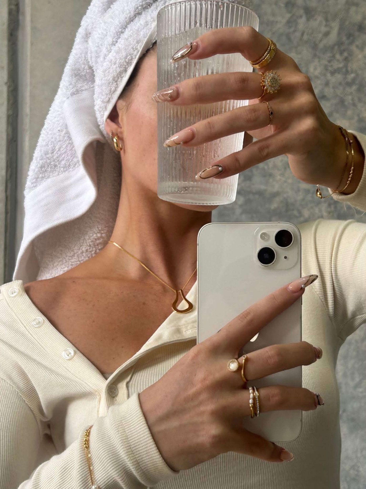 Person holding a phone with a clear glass and wearing gold jewelry.