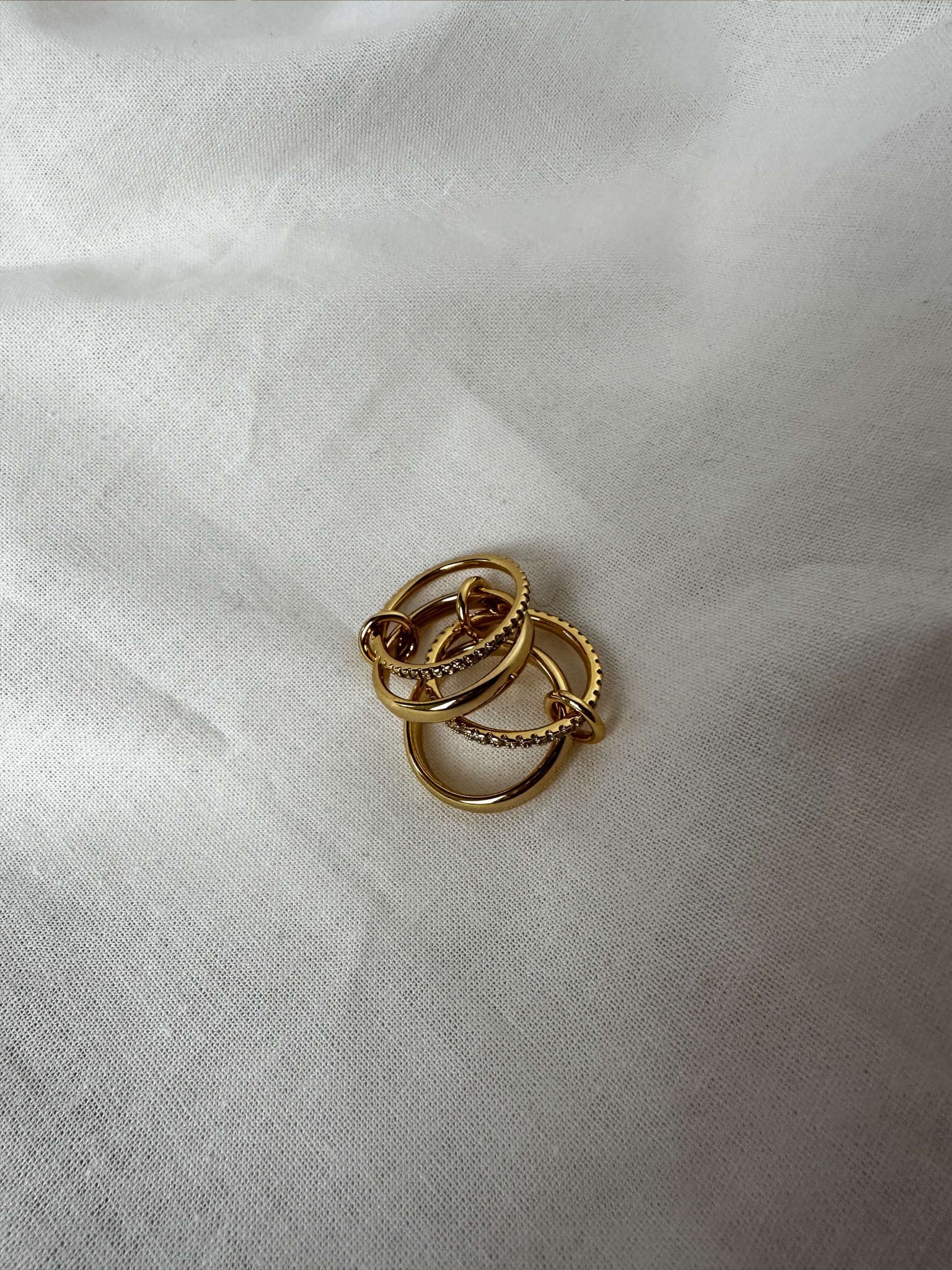 Three gold rings stacked on a white fabric background