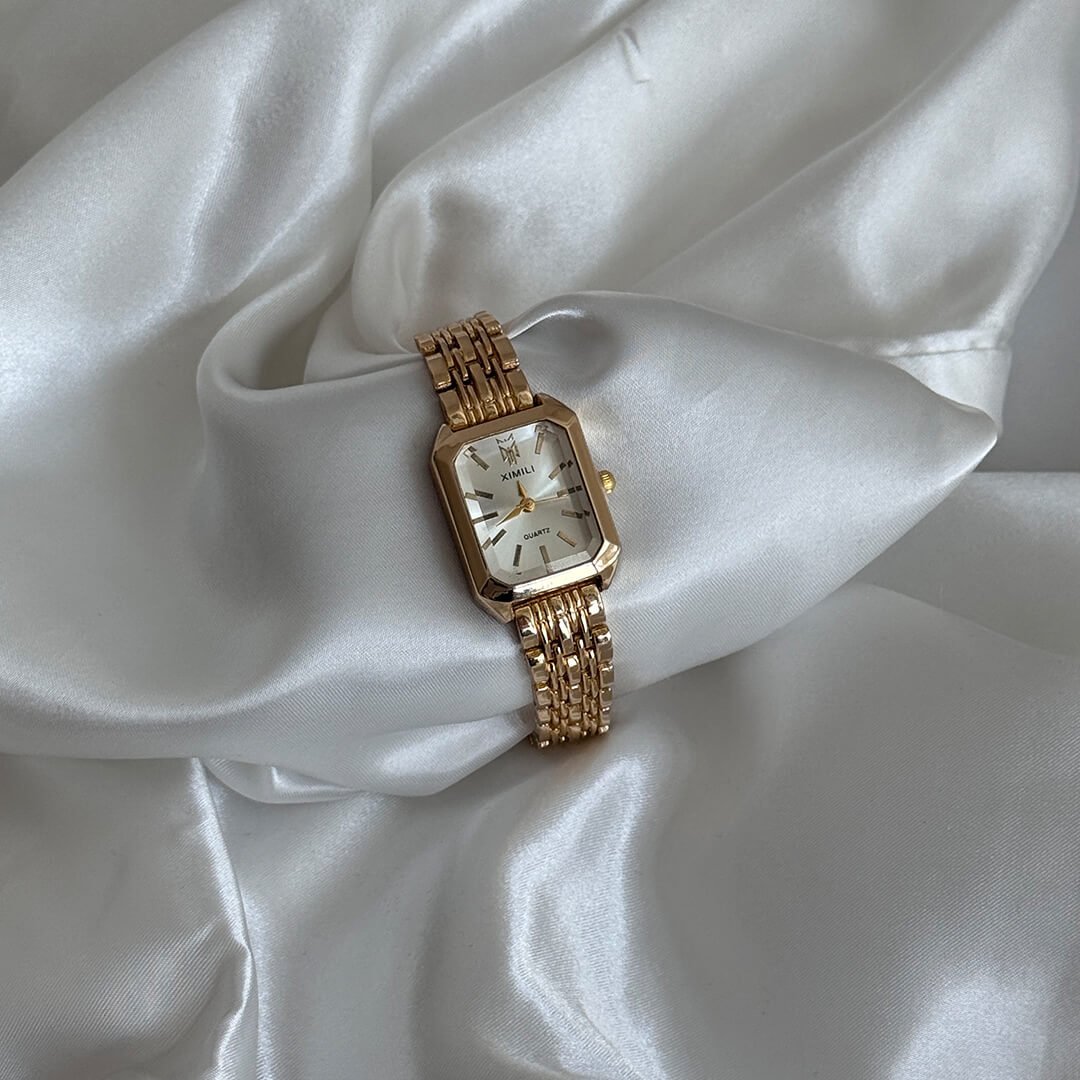 Gold wristwatch on a white satin surface