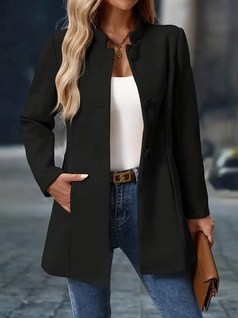 Black tailored jacket with clean lines and collarless neckline, worn open over white top and jeans.