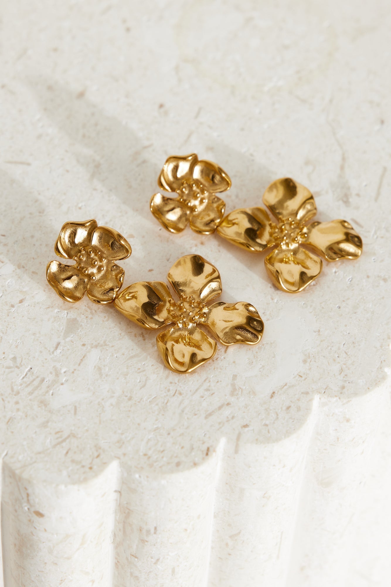 Women's gold flower dangle earrings — detail shot