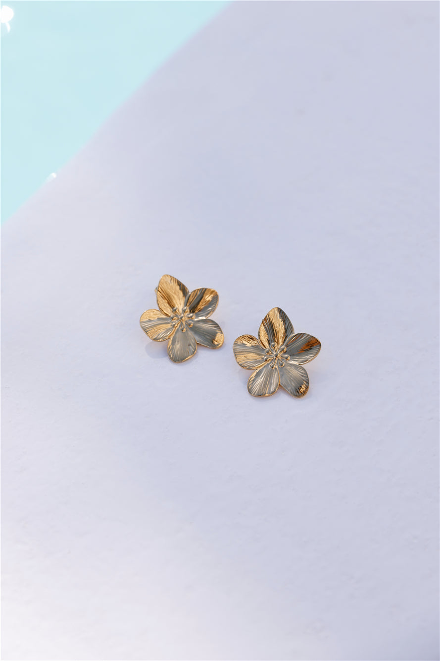 Women's gold flower stud earrings — detail shot