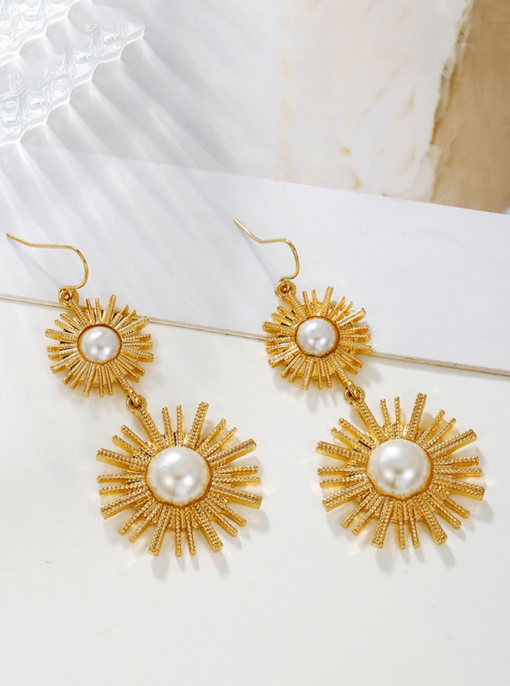 Women's gold sunburst pearl drop earrings — alternate angle