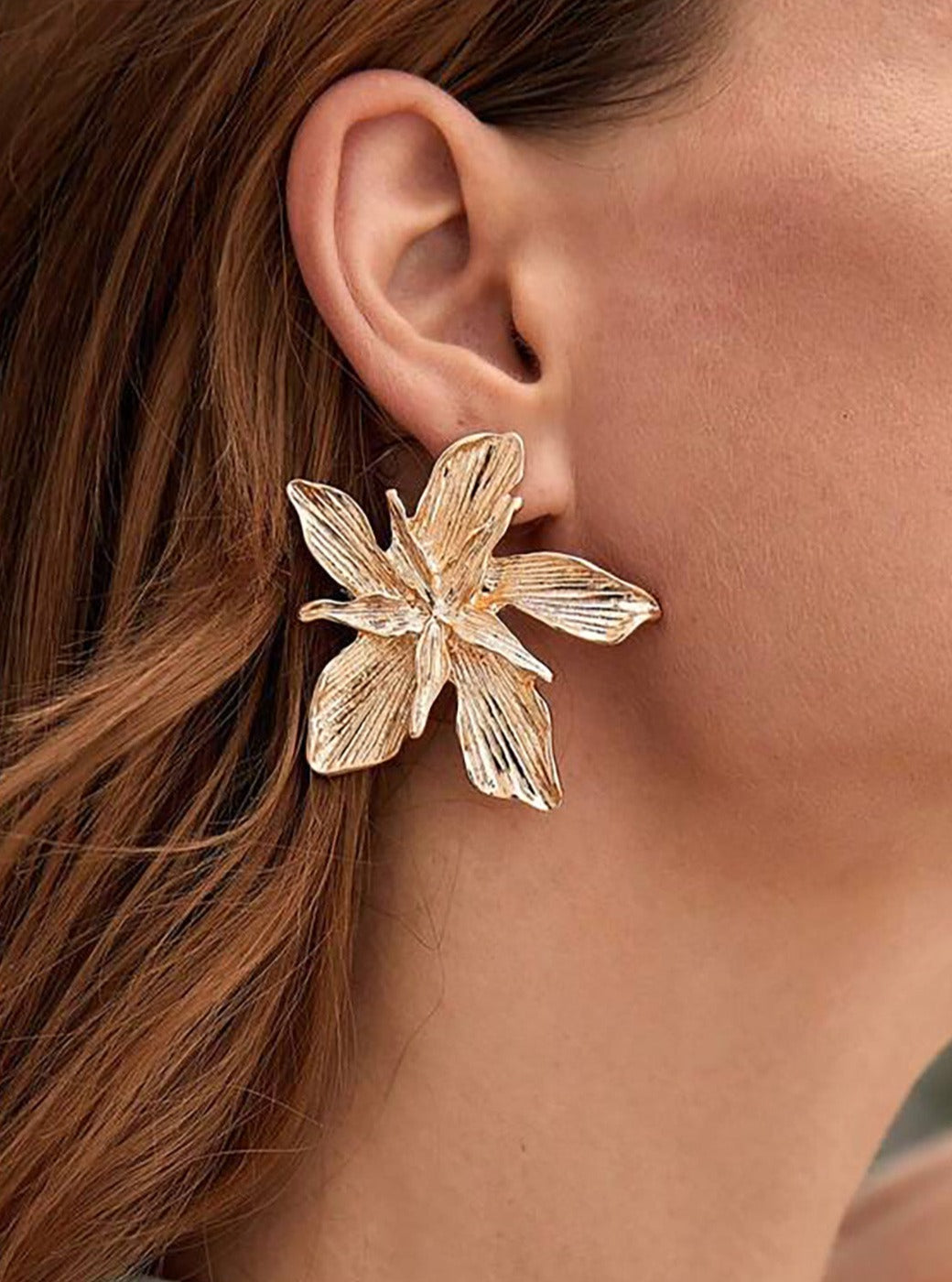 Women's gold metal flower earrings — close-up